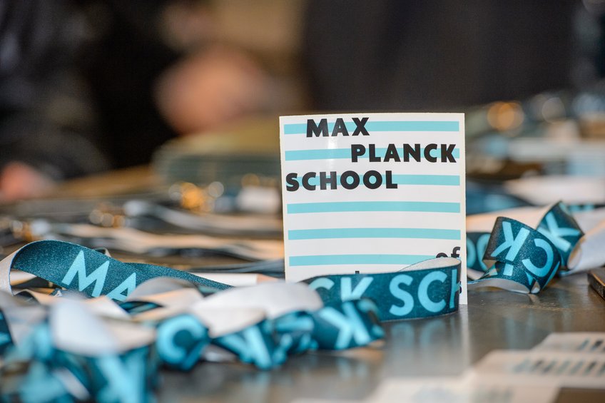 Namensschilder und Bänder der Max Planck School liegen auf einem Tisch bereit.