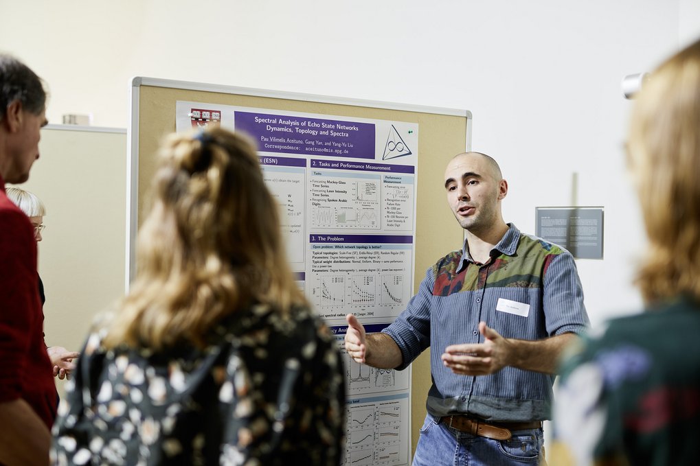 A student explains his research poster to others.