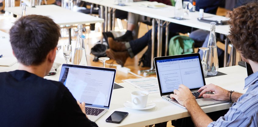 Programm Zwei Personen tippen auf Laptops, während sie an einem Seminar teilnehmen.